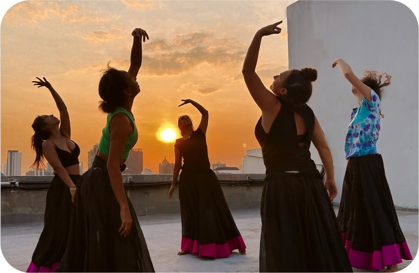 Group participating in a movement therapy class at sunset in the city, following a dance sequence